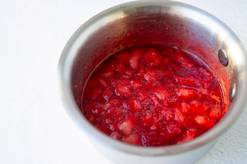 Strawberries cooked in a stainless steel pot.