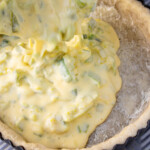 Pouring quiche mixture into a pie crust.