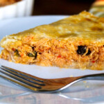 Un trozo de pastel de polvorosa de pollo, con un tenedor, en un plato blanco.