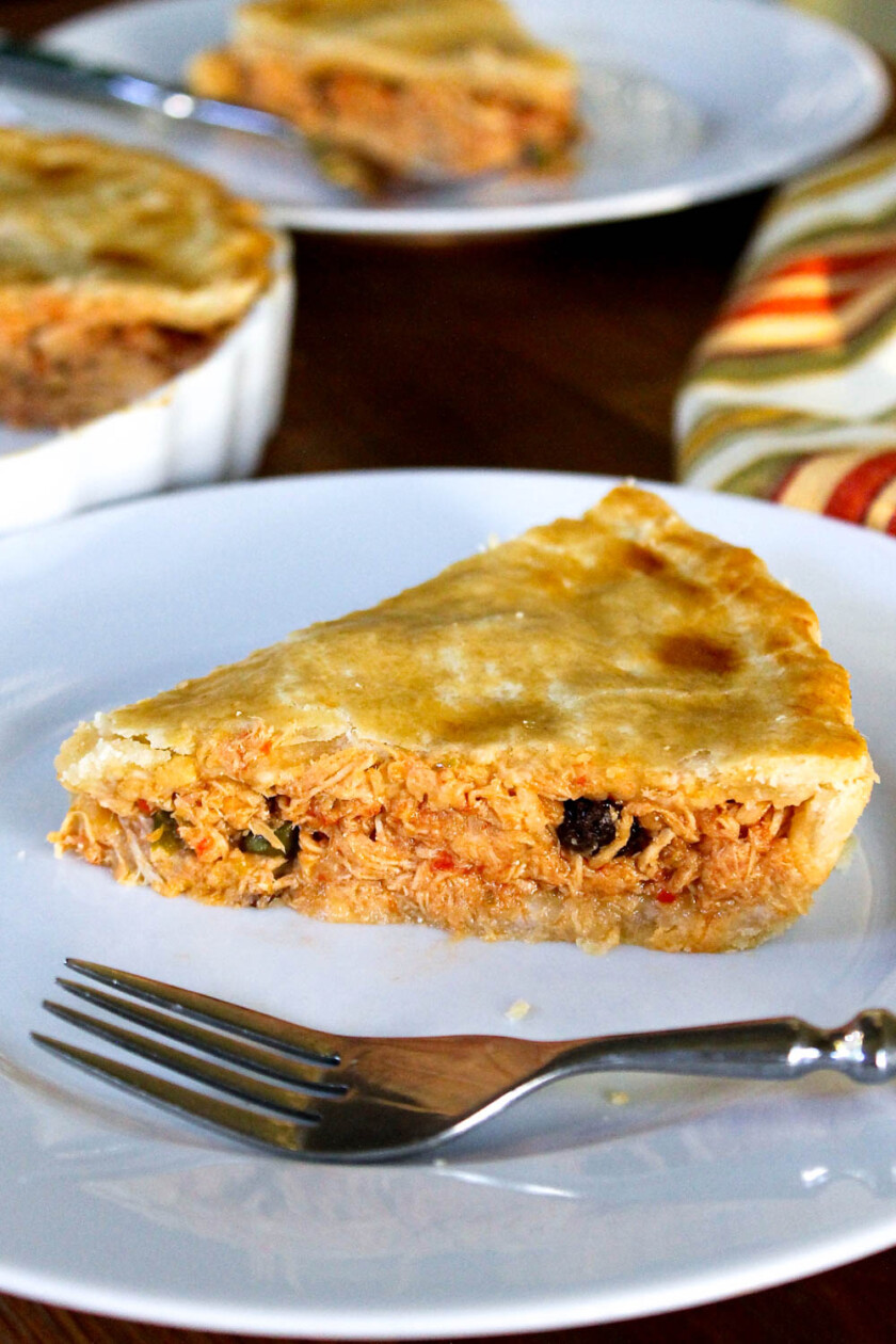 Un trozo de pastel de polvorosa de pollo, con un tenedor, en un plato blanco.