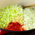 Una olla llena de verduras picadas y una cuchara de madera.