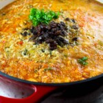 Una olla de hierro colado llena de guiso de polvorosa de pollo en plena preparación.