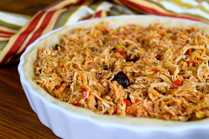 Guiso de pollo desmenuzado en un molde para pastel sobre una mesa.Así se hace la polvorosa de pollo.