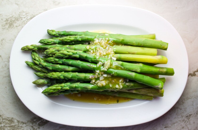 Vinaigrette-Asparagus-by-enrilemoine-1 Espárragos cocidos con vinagreta en un plato ovalado blanco.