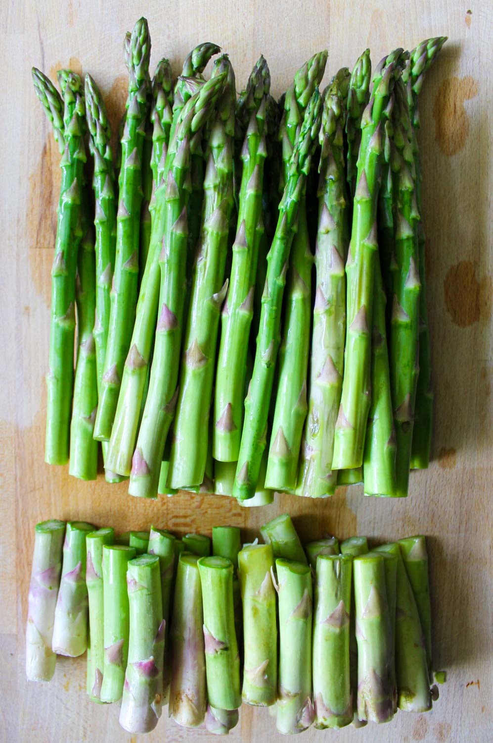 Green asparagus, bottom cut, over a wooden surface.