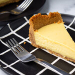A slice of cheesecake on a black and white geometric plate.