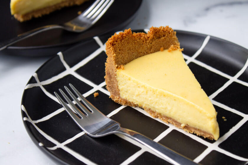 A slice of cheesecake on a black and white geometric plate.