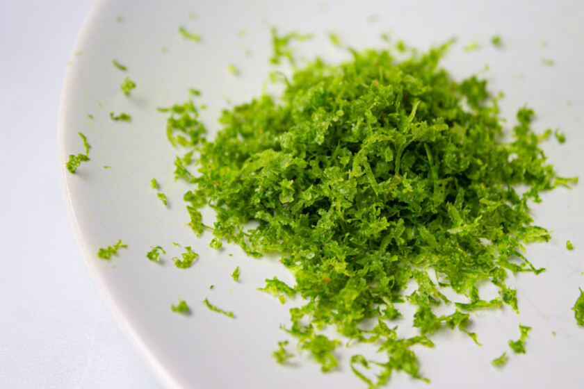Pile of finely grated lime zest on a white plate,