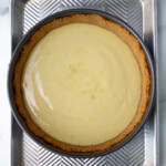 Una tarta de lima con relleno suave y corteza dorada, colocada en una bandeja de metal sobre una superficie de mármol.