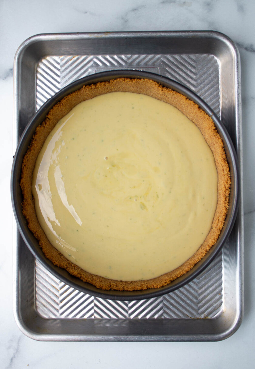 A key lime pie in a metal baking tray with a graham cracker crust and smooth, lime-infused filling.