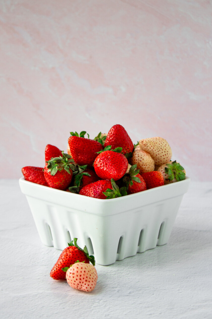 Una cesta llena de fresas frescas sobre un fondo claro.