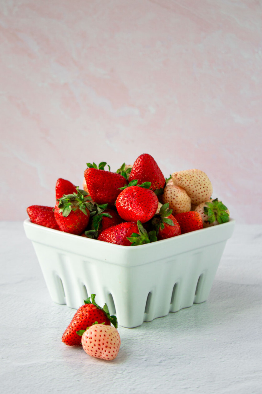 Una cesta llena de fresas frescas sobre un fondo claro.