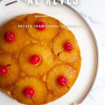 Un tradicional pastel de piña venezolano, "pastel de piña al revés", decorado con rodajas de piña y cerezas, servido en un plato blanco.