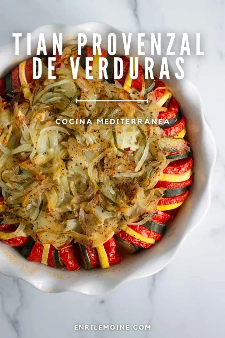 Un plato blanco redondo relleno con rodajas de calabacín, tomate y calabaza amarilla cuidadosamente dispuestas, cubierto con cebollas cocidas y hierbas. Perfecto para descubrir qué es un tian provenzal de verduras.