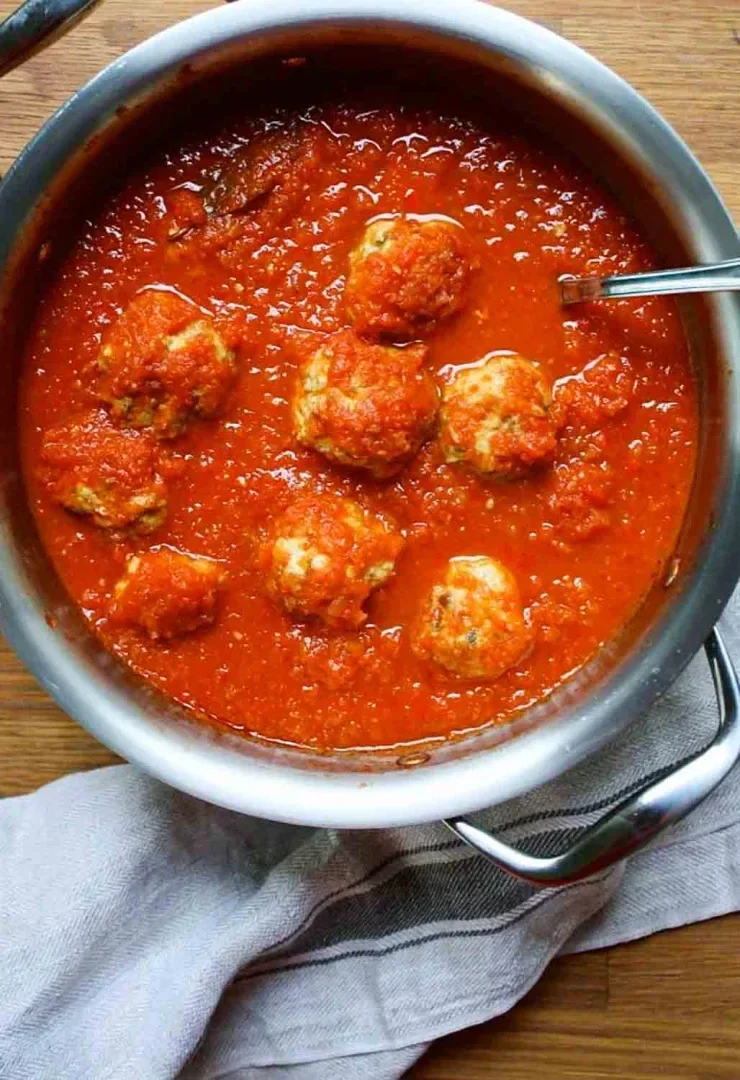Una olla de acero inoxidable llena de albóndigas cochino en salsa de tomate.