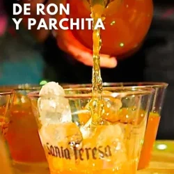 Jarra vertiendo una guarapita de ron y parchita, en un vaso con hielo desechable, donde se lee Santa Teresa. Hay un texto donde se lee la frase Receta de guarapita de ron y parchita.