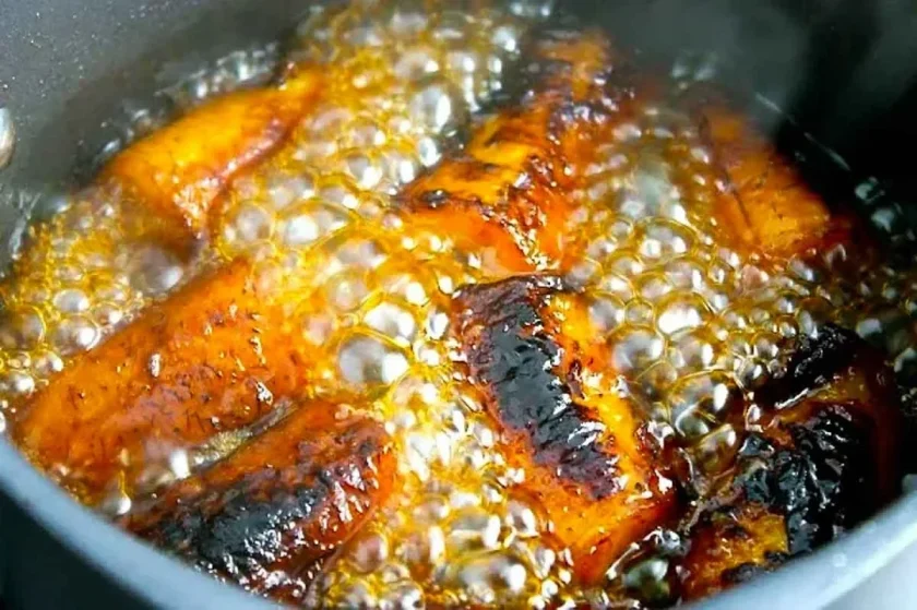 Pieces of golden plantains, being cooked in a syrup.
