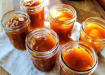 Seis envases de vidrio sin tapa, rellenos de mermelada de guayaba.