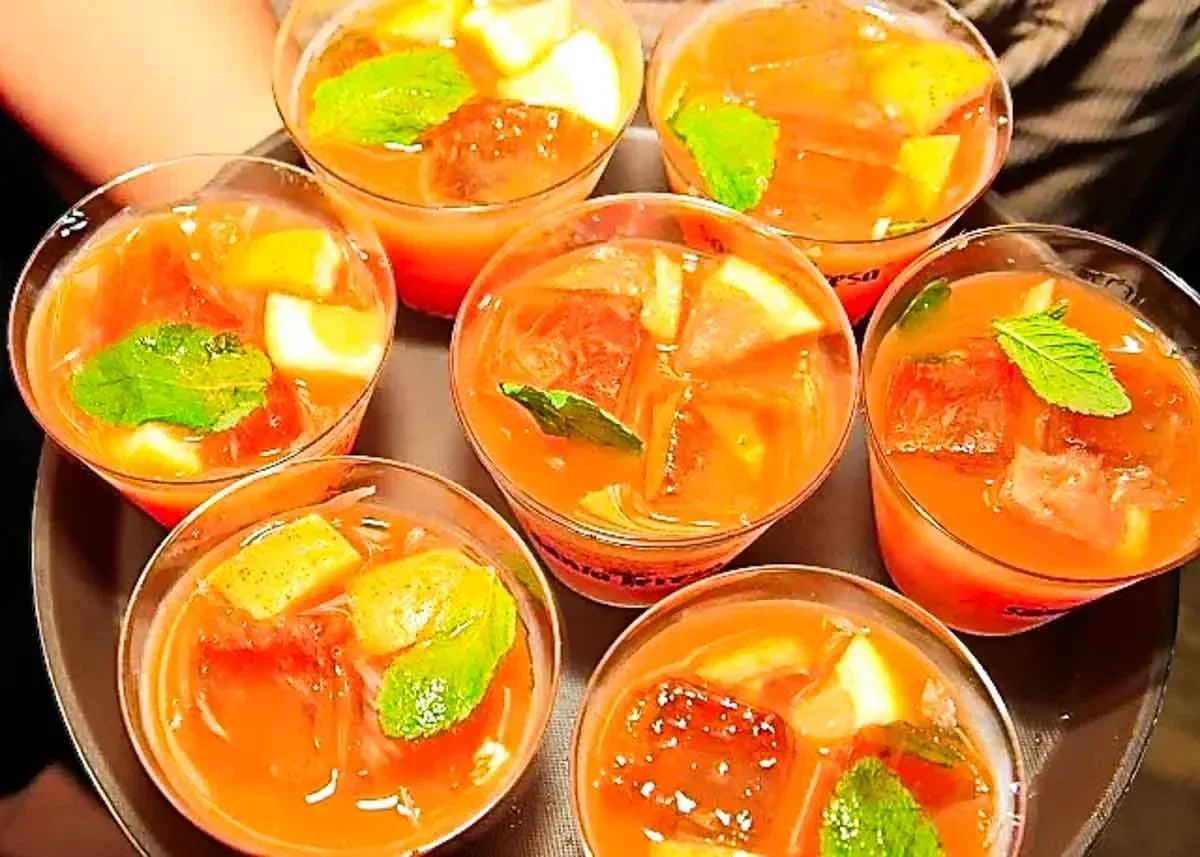 Siete vasos de guarapita de ron y parchita, con trozos de limón y hojas de yerbabuena por encima. Los vasos están dispuestos en una bandeja.
