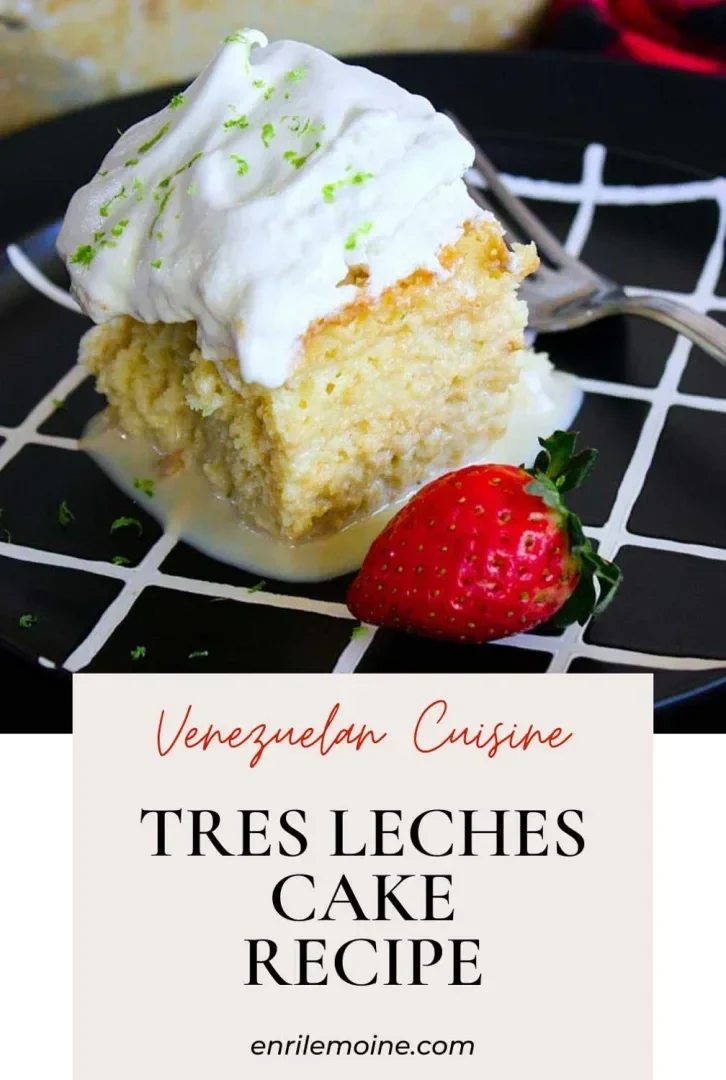A slice of tres leches cake with meringue and lime zest, served with a strawberry on a black plate.