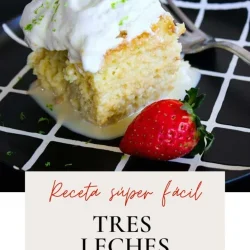 Un trozo de tarta tres leches con nata montada y una fresa en un plato negro con líneas de cuadrícula blancas.