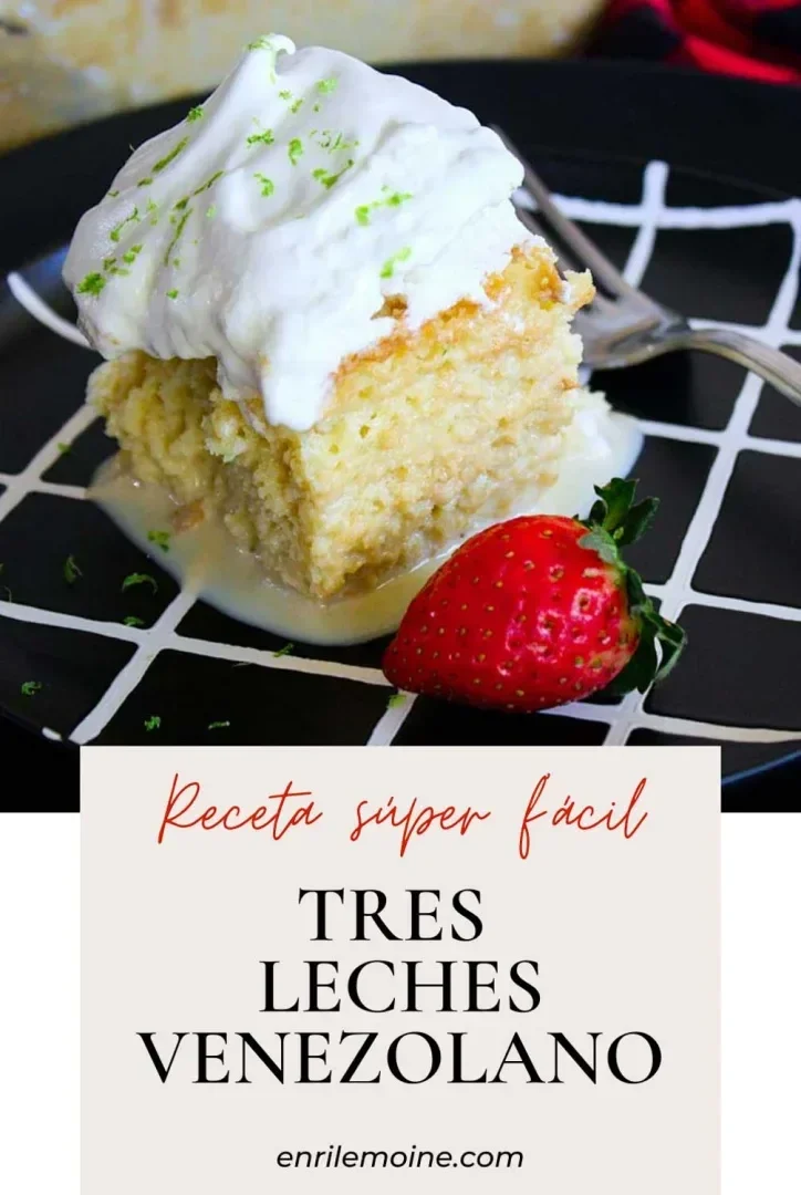 Un trozo de tarta tres leches con nata montada y una fresa en un plato negro con líneas de cuadrícula blancas.
