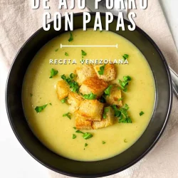 Un cuenco de crema de puerro y patata con picatostes y perejil, sobre una servilleta beige.