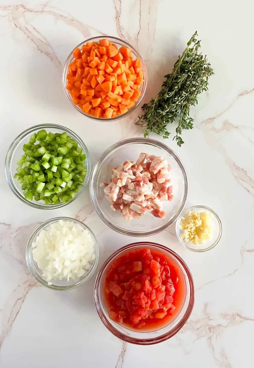 Tazones de vidrio con zanahoria, apio, cebolla, tocineta,tomate, ajo, todo picadito, parahacer el sofrito de una sopa de alubias.
