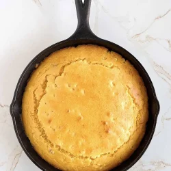 Golden cornbread baked on.a cast iron skillet.
