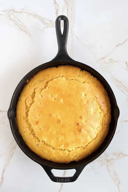 Golden cornbread baked on.a cast iron skillet.