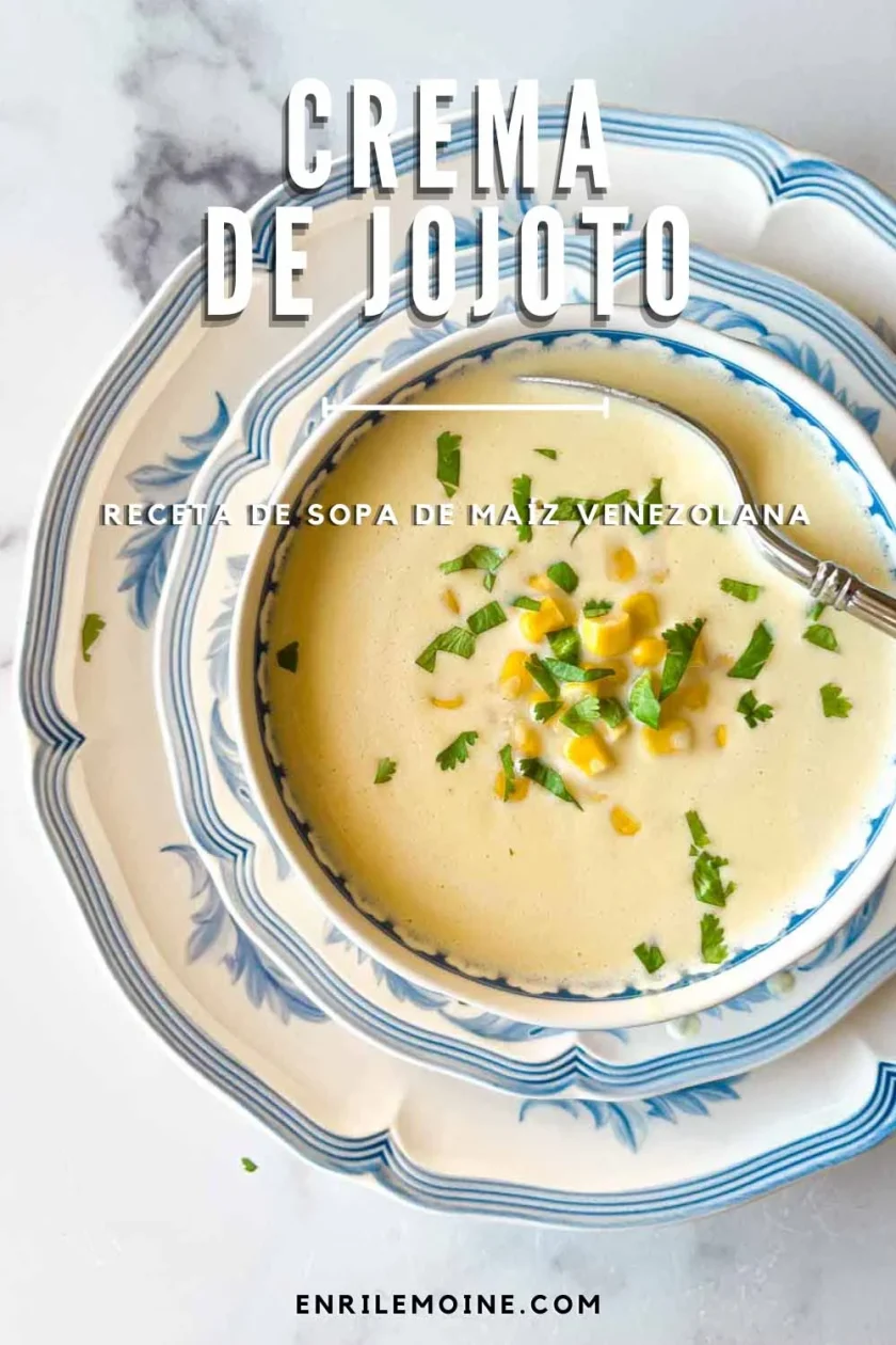 Tazón de sopa cremosa de maíz con guarnición de maíz y hierbas, servido en platos florales con cuchara.