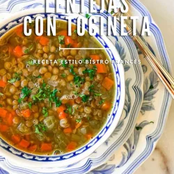 Tazón de sopa de lentejas con verduras y tocino, cubierto de hierbas, en un plato estampado con una cuchara.
