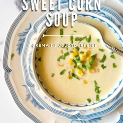 Bowl of creamy crema de jojoto venezolana, a classic sweet corn soup, garnished with corn and herbs on blue and white dishes.