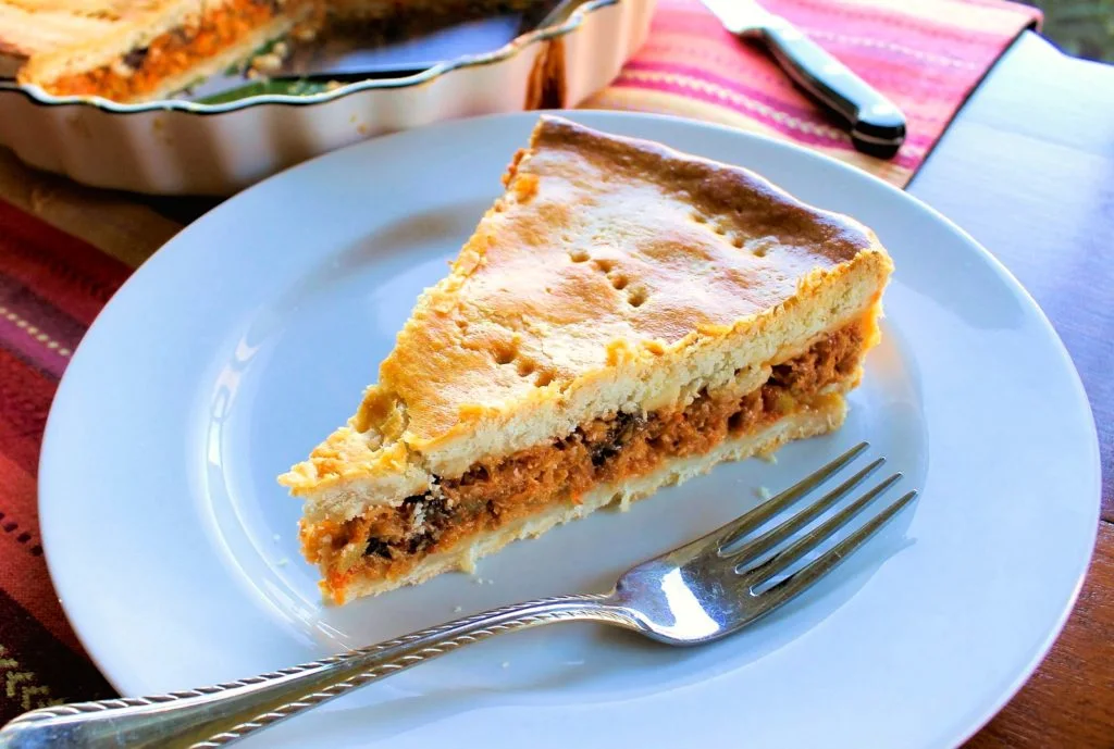 Un trozo de polvorosa de atún sobre un plato blanco con un tenedor.