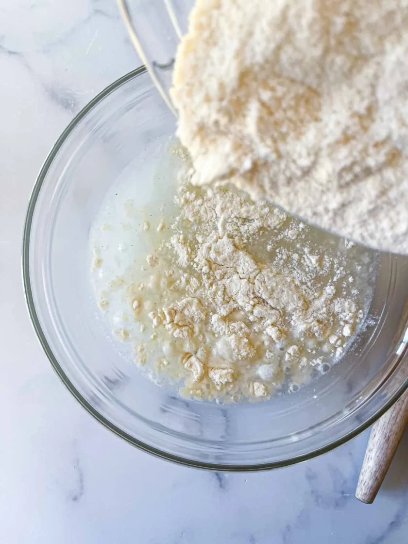 Harina de arepas cayendo sobre un bol de vidrio, para hacer masa de arepas.