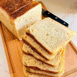 A loaf of sliced sourdough sandwich bread on a wooden cutting board with a knife next to it, perfect for your favorite sourdough sandwich bread recipe.