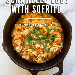 A cast-iron skillet with Perico, Venezuelan scrambled eggs with sofrito, topped with fresh herbs.