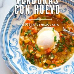Tazón de sopa de verduras venezolana con un huevo escalfado, adornado con hierbas, en un plato azul y blanco.