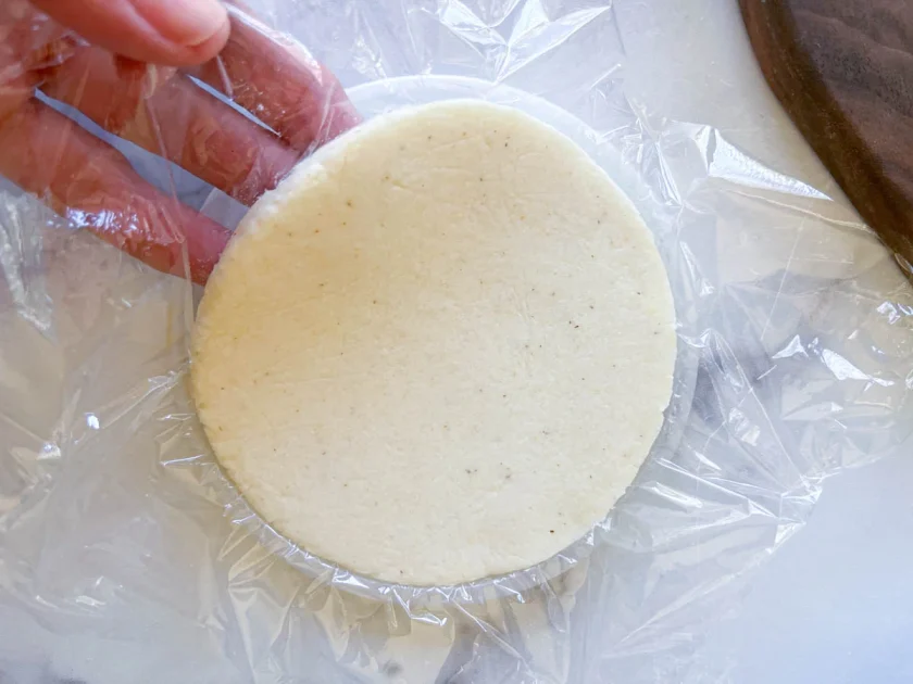 Una mano despega una arepa de una tapa plástica