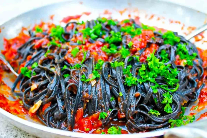 Pasta alla puttanesca - SAVOIR FAIRE by enrilemoine Linguine negro alla puttanesca en un sartén, espolvoreado todo con perejil fresco.