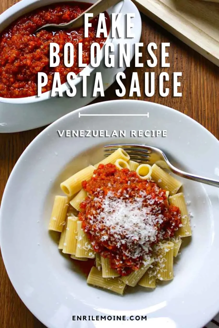A bowl of rigatoni dressed with fake Bolognese sauce and Parmesan cheese, on a wooden surface.