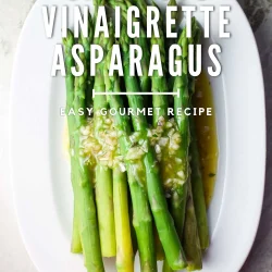 asapagus with a shallot vinaigrette on white oval dish over a marble surface.