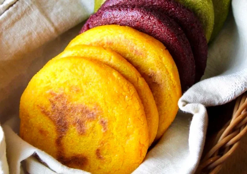  veggie-colored arepas on a beige linen towel.