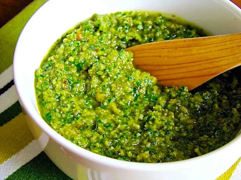 Un tazón blanco con pesto de rúcula y nueces.