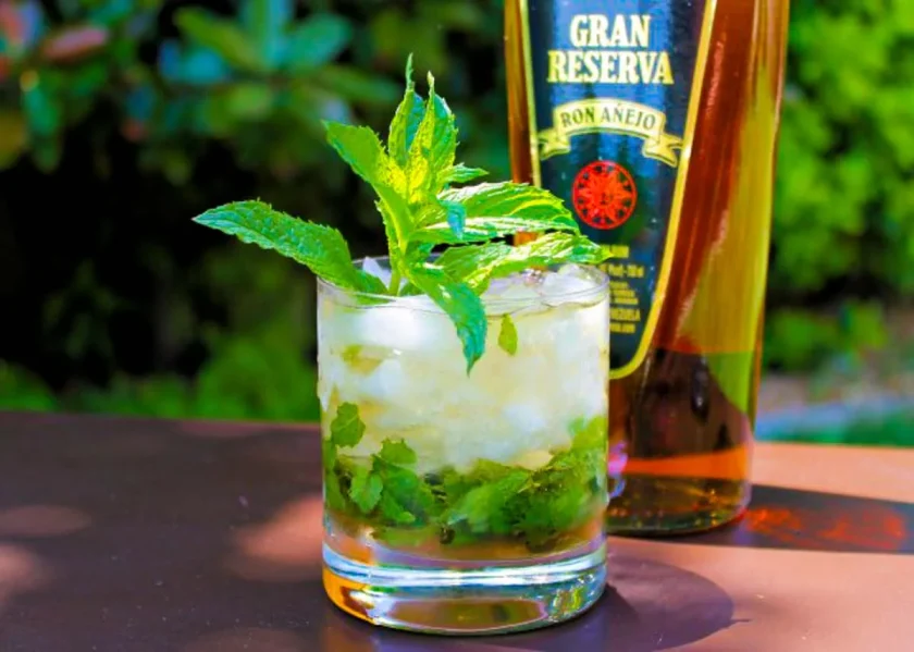 a rum mint julep with a bottle of rum on the background