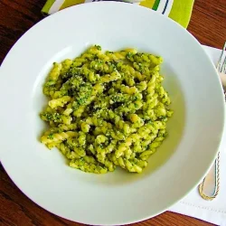 A white bowl with pasta with arugula and walnut pesto