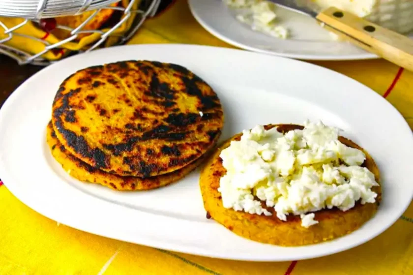 arepas de plåtano con queso blanco en un plato blanco ovalado.