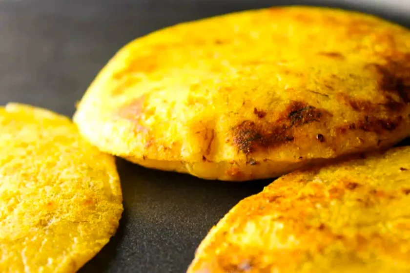 primer plano de unas arepas de plátano en un mudare, ya abombándose.