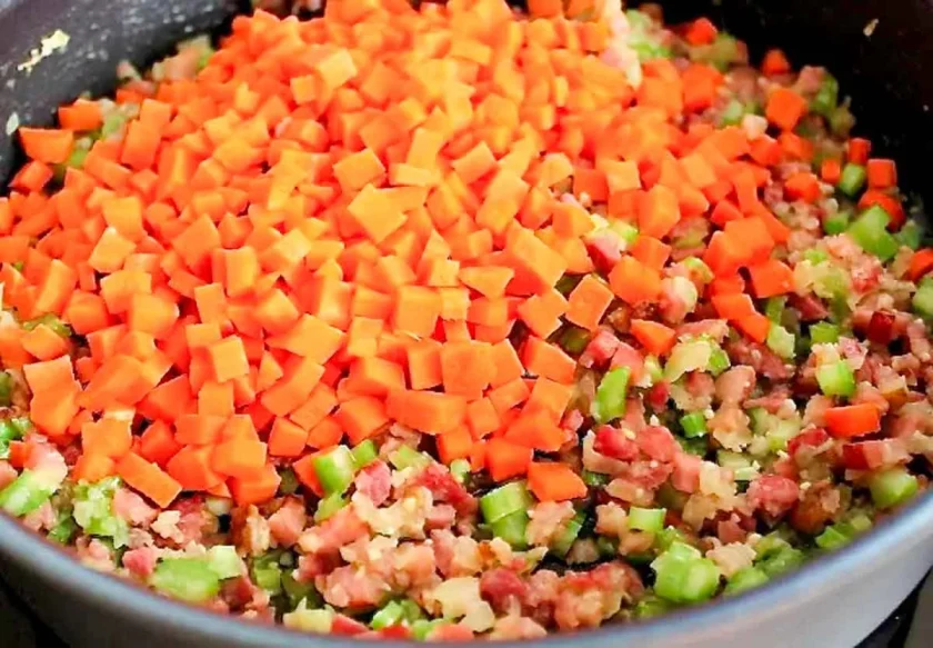 un sarten porofundo con sofrito para hacer sopa de arvejas con jamon y zanahorias en mini cubitos.