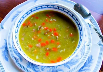 sopa de arvejas con jamón en un bol blanco con arabescos en azul.